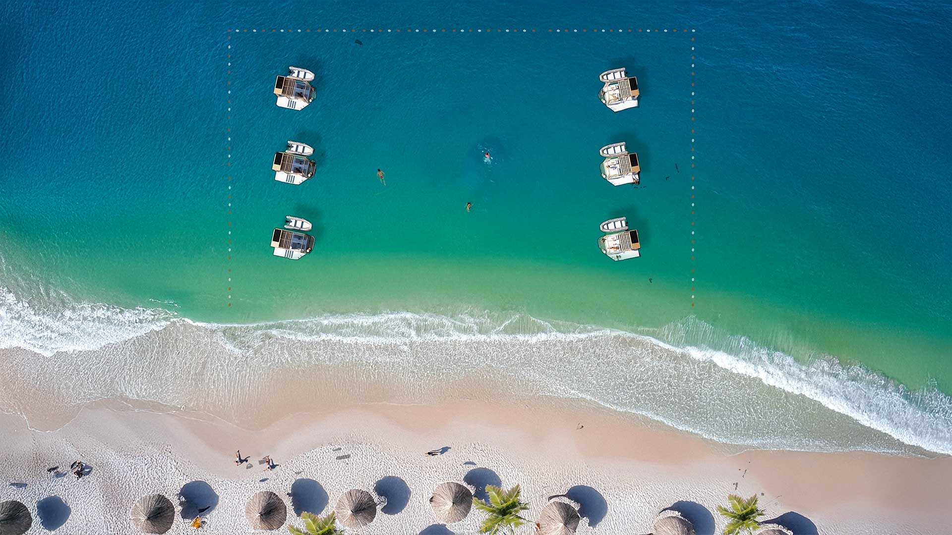 Aerial view of multiple luxury Floating Lounges aligned on a turquoise beachfront, offering exclusive relaxation spaces for beachgoers.